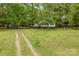 Spacious front yard with a long driveway leading to a charming home surrounded by mature trees at 124 Neumann Run, Belmont, NC 28012