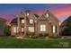 Stately brick home featuring manicured lawn, lush landscaping, and classic architectural details at 13420 Robert Walker Dr, Davidson, NC 28036