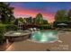 Beautiful backyard pool and spa with rock waterfall feature and brick paver patio under a colorful sunset at 13420 Robert Walker Dr, Davidson, NC 28036