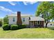Charming exterior of a home featuring a brick chimney, covered porch with seating, and a well-maintained lawn at 155 Jackson Rd, Salisbury, NC 28146
