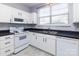 Efficient kitchen layout featuring white appliances, dark countertops, mosaic backsplash, and ample natural light at 1716 Termini Dr, Charlotte, NC 28262