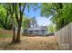 A blue home with a small wood deck sits in a large yard bordered by a wood fence at 1913 Garibaldi Ave, Charlotte, NC 28208