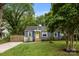 Quaint blue home with a bright yellow door, mature trees, and a concrete driveway and walkway at 1913 Garibaldi Ave, Charlotte, NC 28208