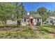 Quaint one-story home featuring a red front door, gray siding and mature trees at 1944 Garibaldi Ave, Charlotte, NC 28208