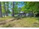 Charming gray home with a cozy front porch surrounded by lush greenery and mature trees at 2601 Dora Dr, Charlotte, NC 28215