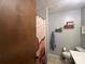 Bathroom with a shower featuring a patterned shower curtain, toilet with shelving decor, and beige tile floors at 33611 Mann Rd, Albemarle, NC 28001