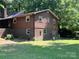 Back exterior showcasing a brick foundation, wood siding, and multiple windows at 33611 Mann Rd, Albemarle, NC 28001