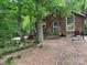 Charming brown home with a blue door, large window, and wooden deck nestled among mature trees at 33611 Mann Rd, Albemarle, NC 28001