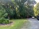 Spacious front yard with green grass, mature trees, and gravel driveway leading to the house at 33611 Mann Rd, Albemarle, NC 28001