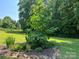 Beautiful front yard with green grass, a vibrant tree and shrub, and decorative rock edging at 33611 Mann Rd, Albemarle, NC 28001
