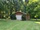 Detached garage with a single white door and brown trim surrounded by lush greenery at 33611 Mann Rd, Albemarle, NC 28001
