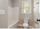 Well-lit bathroom showcases a sleek toilet, bathtub, and window providing natural light at 5162 Beckenham Ln, Concord, NC 28025