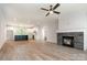 Open-concept living room featuring a stone fireplace, hardwood floors, and a modern ceiling fan at 5162 Beckenham Ln, Concord, NC 28025