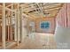 Unfinished living room featuring exposed framing, pink insulation, and a window to the outside at 530 Gantt St, Mooresville, NC 28115