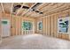 A spacious, unfinished living room with exposed studs, two windows, and a door at 530 Gantt St, Mooresville, NC 28115