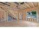 An unfinished living room features exposed framing, a staircase, and natural light from a window at 530 Gantt St, Mooresville, NC 28115