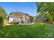 A landscaped backyard featuring a wooden pergola, a fire pit, and a lush lawn at 6002 Sentinel Dr, Indian Trail, NC 28079