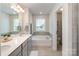 Bright bathroom featuring double vanity, soaking tub, and neutral tile flooring at 9102 Buckley Ct, Charlotte, NC 28269