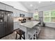 Open-concept kitchen featuring stainless steel appliances, granite countertops, an island with seating and gray cabinets at 11104 Pine Grove Ave, Mint Hill, NC 28227