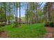 Expansive backyard with lush green lawn, mature trees, and an elegant grey home in the background at 116 Anderson Farm Ct, Mooresville, NC 28117