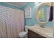 Bathroom with blue walls, a white vanity, toilet, and a shower with a patterned curtain at 1238 Moss Springs Rd, Albemarle, NC 28001