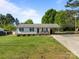 Charming single-story home featuring manicured lawn, carport, and inviting front porch with cozy bench seating at 1238 Moss Springs Rd, Albemarle, NC 28001