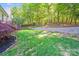 Lush backyard with a retaining wall, grass, garden beds, and mature trees surrounding the property at 13817 Kings Carriage Ln, Charlotte, NC 28278