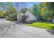 A suburban home featuring an attached garage, landscaped yard, and mature trees at 13817 Kings Carriage Ln, Charlotte, NC 28278