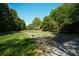 A serene green space with lush trees and manicured lawn offers a tranquil escape and natural beauty at 13817 Kings Carriage Ln, Charlotte, NC 28278