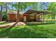 Backyard view of a brick home featuring a covered carport and green lawn at 1501 Briarfield Dr, Charlotte, NC 28205