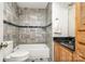 Compact bathroom featuring a shower-over-tub, black granite countertop, and stylish gray tile at 1600 Sharon W Rd # 8, Charlotte, NC 28210