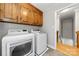 Functional laundry room with wood cabinets, a modern washer and dryer, and access to stairs at 16614 Beech Hill Dr, Huntersville, NC 28078