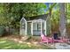 Charming backyard playhouse with a porch and two chairs, nestled among trees and lush landscaping at 16614 Beech Hill Dr, Huntersville, NC 28078