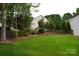 Picturesque backyard with a sloping lawn, framed by a wooden fence and mature trees, perfect for outdoor enjoyment at 2624 St Helena Ct, Fort Mill, SC 29715