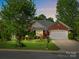 Beautiful brick home at dusk with manicured lawn, flower beds, and an inviting two-car garage at 281 Loch Stone St, Fort Mill, SC 29715