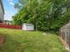Backyard view of a shed with lawn and a red fence at 3022 Willamette Valley Dr, Charlotte, NC 28215
