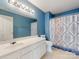 A full bathroom with a white vanity, blue walls, and shower with patterned curtain at 3022 Willamette Valley Dr, Charlotte, NC 28215