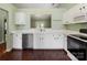 Well-lit kitchen featuring white cabinets, stainless steel appliances, a serving pass-through, and dark wood floors at 3022 Willamette Valley Dr, Charlotte, NC 28215