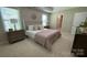 Relaxing bedroom with a tray ceiling, plush bedding, and natural light from the bright windows and walk-in closet at 3030 Collin House Dr, Fort Mill, SC 29715