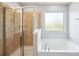 Bright bathroom showcasing a separate shower with tile surround and a soaking tub with a large window at 4011 Black Walnut Way, Indian Land, SC 29707