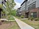A row of townhomes features gray siding, brick accents, and well-maintained landscaping along the walkways at 417 Tristram Ln, Charlotte, NC 28205