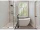 Modern bathroom with a freestanding tub, glass shower with designer tile accent wall and large window with bright natural light at 5538 Camelot Dr, Charlotte, NC 28270