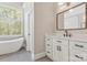 Modern bathroom featuring a soaking tub, white cabinetry, quartz countertops and a framed mirror at 5538 Camelot Dr, Charlotte, NC 28270
