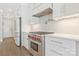 Close up of a modern kitchen featuring stainless steel appliances, a range hood, and white cabinetry at 5538 Camelot Dr, Charlotte, NC 28270