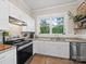 Bright kitchen boasts white cabinets, granite counters, a black range, and a charming view of the outdoors at 705 N Fulton St, Salisbury, NC 28144