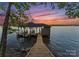 Beautiful boathouse on stilts with a wooden walkway leading to the water under pink sunset at 8058 Edgewater Dr, Norwood, NC 28128