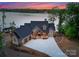 Charming lakefront home with stone accents, three-car garage, and sunset sky at 8058 Edgewater Dr, Norwood, NC 28128