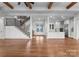 Bright and spacious living area featuring hardwood floors, open staircase, and a modern kitchen with stainless steel appliances at 8058 Edgewater Dr, Norwood, NC 28128