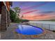 Outdoor pool with pavers and lake views at dusk, complete with black metal fencing at 8058 Edgewater Dr, Norwood, NC 28128