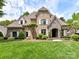 Elegant brick and stone home showcasing a meticulously landscaped lawn and charming architectural details at 825 Hudson Pl, Davidson, NC 28036